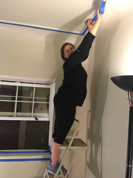Person on ladder taping ceiling before painting