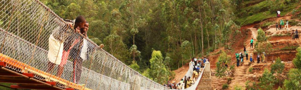 People walking on long hanging bridge structure in underdeveloped country